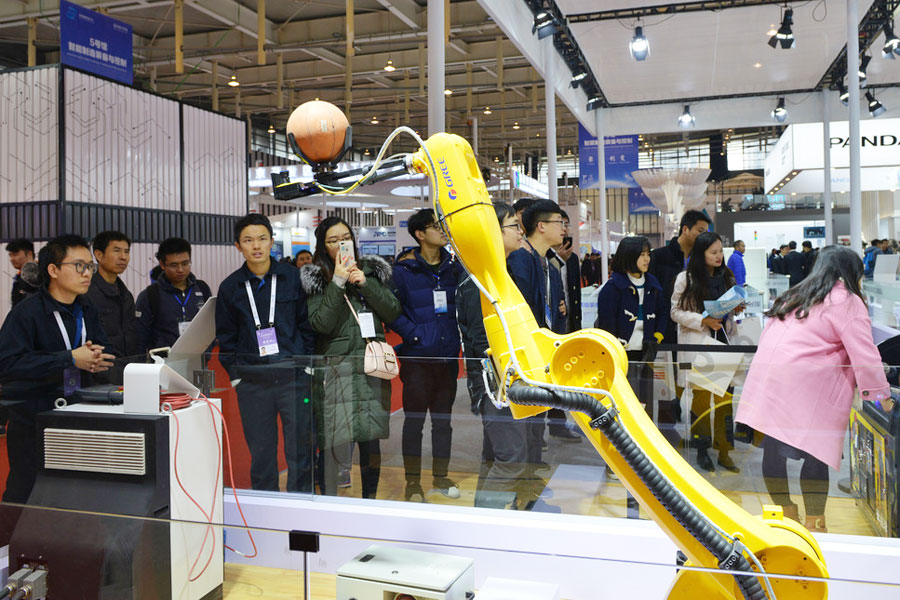 La gente observa un robot que lanza pelotas de baloncesto en la Cumbre Mundial de Fabricación Inteligente en Nanjing, provincia de Jiangsu, el 6 de diciembre de 2017. [Foto / IC]