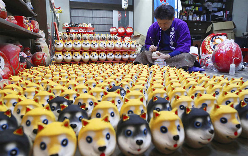 Un artesano japonés trabaja en muñecos daruma con rostros de perros, el animal regente del zodíaco chino durante el 2018, 24 de noviembre del 2017. [Foto: IC]