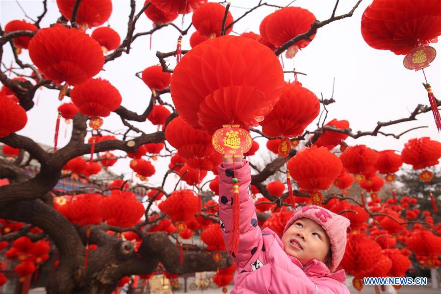 Un niño juega con los faroles rojos que embellecen la puerta sur del parque Ditan, conocido también como el parque del Templo de la Tierra, Beijing, 27 de enero del 2018. [Foto: Xinhua]
