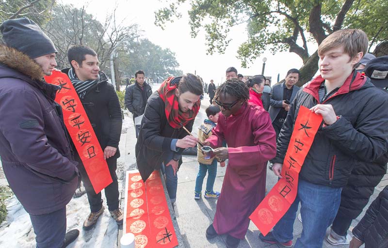 Los estudiantes extranjeros escriben coplas usando caligrafía china en el Lago Oeste de Hangzhou, capital de la provincia de Zhejiang, el 2 de febrero de 2018. [Foto / IC]