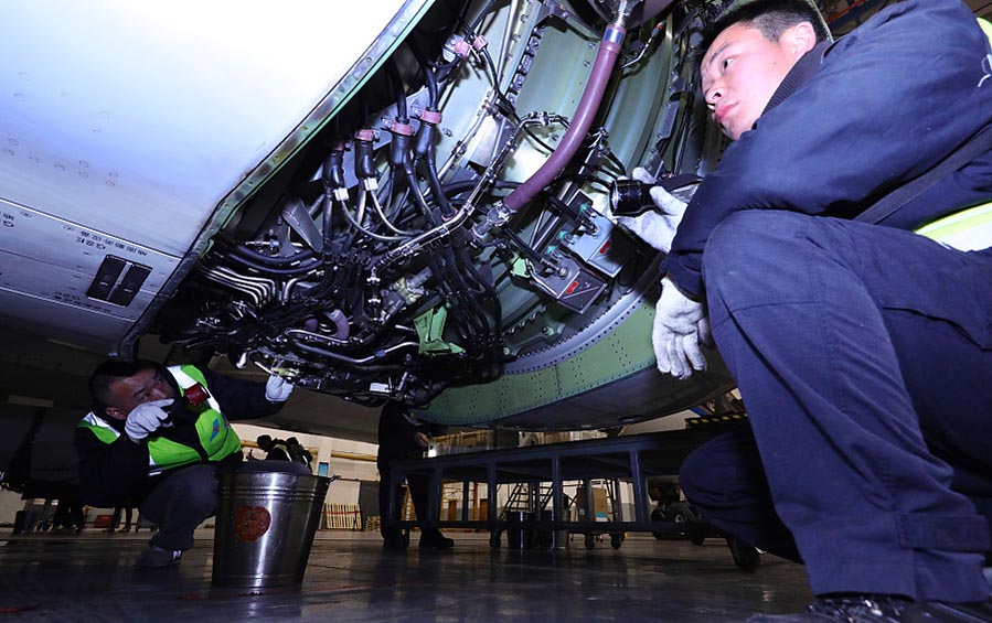Dos ingenieros comprueban los circuitos interiores de un avión en un centro de mantenimiento en la ciudad de Wuhan que trabaja para la aerolínea China Southern, provincia de Hubei, 9 de febrero del 2018. [Foto: VCG]
