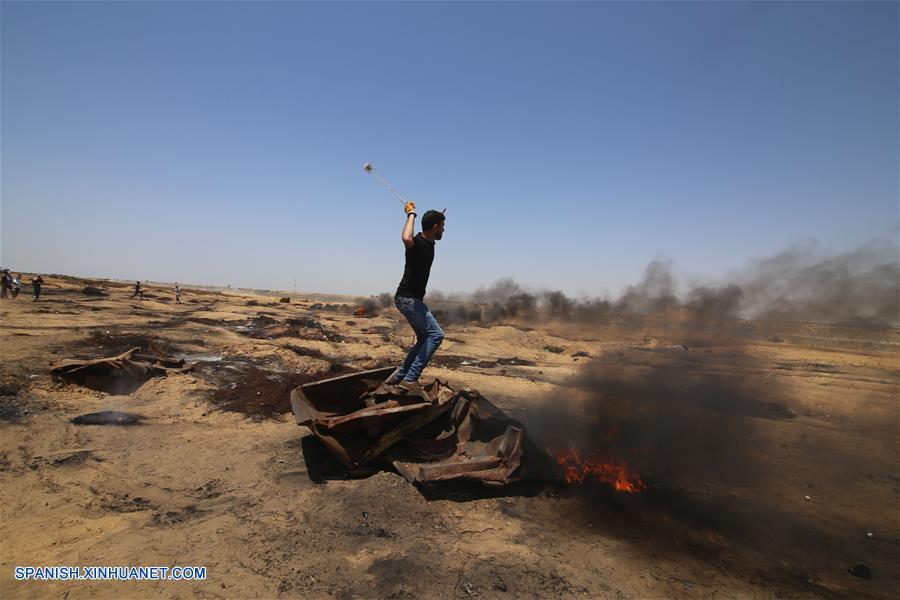 Un manifestante palestino usa una honda para lanar una piedra a los soldados israelíes durante los enfrentamientos con soldados israelíes, en la frontera de Gaza e Israel, en el este de la ciudad de Khan Younis del sur de la Franja de Gaza, el 8 de junio de 2018. (Xinhua/Khaled Omar)