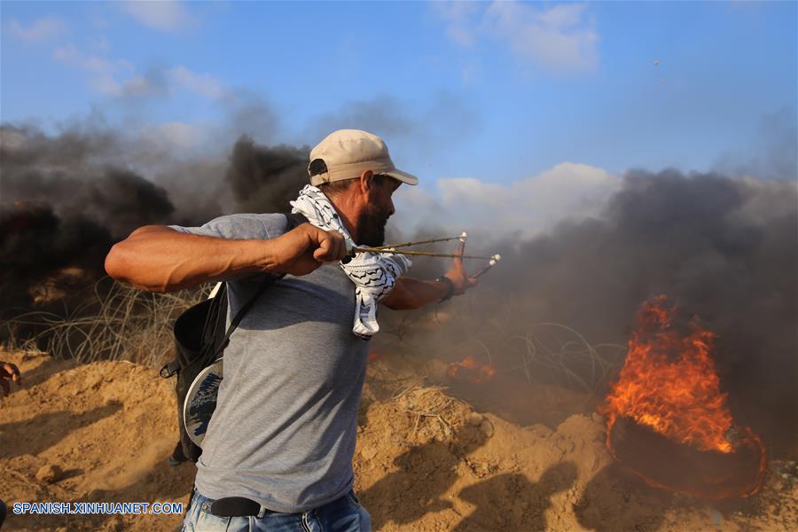 GAZA, agosto 3, 2018 (Xinhua) -- Un manifestante palestino utiliza una honda para lanzar piedras a soldados israelíes durante enfrentamientos en la frontera entre Gaza e Israel, en el este de la Ciudad de Gaza, el 3 de agosto de 2018. De acuerdo con información de la prensa local, un palestino fue asesinado y otros 220 fueron heridos por soldados israelíes el viernes durante enfrentamientos cerca de la frontera entre Gaza e Israel, informó el vocero del ministro palestino de Salud en la Franja de Gaza. (Xinhua/Khaled Omar)