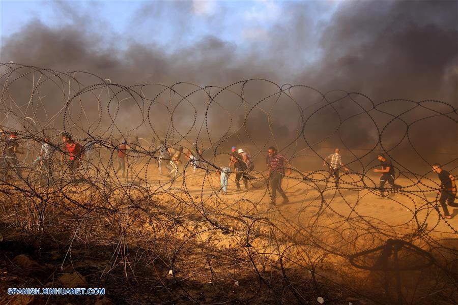 GAZA, agosto 3, 2018 (Xinhua) -- Manifestantes palestinos corren para cubrirse de latas de gas lacrimógeno disparadas por soldados israelíes durante enfrentamientos en la frontera entre Gaza e Israel, en el este de la Ciudad de Gaza, el 3 de agosto de 2018. De acuerdo con información de la prensa local, un palestino fue asesinado y otros 220 fueron heridos por soldados israelíes el viernes durante enfrentamientos cerca de la frontera entre Gaza e Israel, informó el vocero del ministro palestino de Salud en la Franja de Gaza. (Xinhua/Khaled Omar)