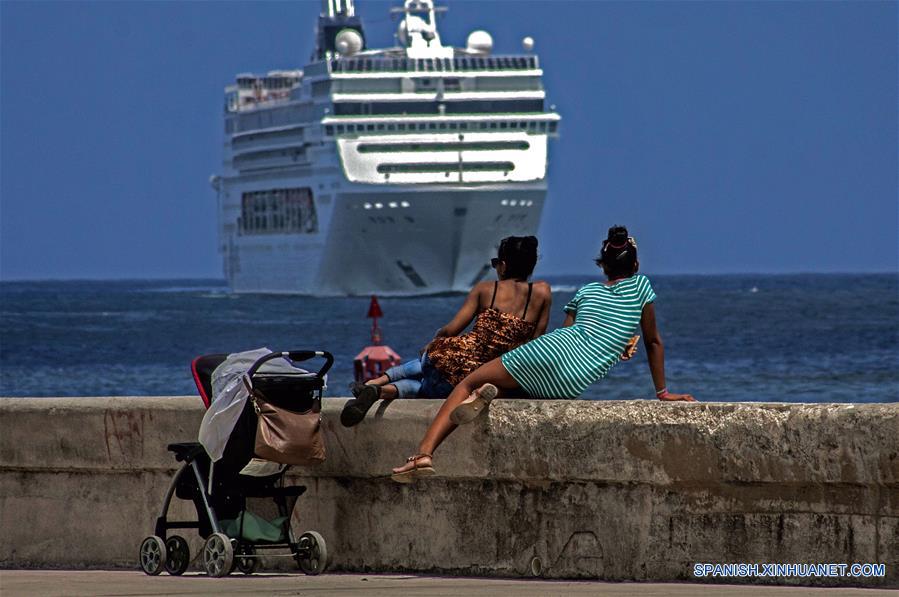 Imagen del 13 de marzo de 2018 de dos mujeres observando la entrada de un crucero a la bahía de La Habana, Cuba. La industria turística cubana, el sector más dinámico de la economía de la isla, se ha desacelerado en lo que va del año como resultado de las medidas restrictivas de la administración del presidente estadounidense Donald Trump. Esta semana, el Ministerio de Turismo de Cuba (MINTUR) informó de la llegada de 3 millones de vacacionistas, una cifra lograda 16 días más tarde que en 2017, la cual confirmó la caída del ritmo de arribos a la isla. Desde 2012, el arribo de vacacionistas extranjeros a Cuba ha mantenido una tasa de crecimiento promedio del 13 por ciento, lo que convirtió a la llamada "Industria del ocio" en una de las principales fuentes de ingresos de la economía cubana. El año pasado, la isla logró la cifra histórica de 4 millones 689.000 visitantes foráneos, cifra que significó un incremento del 16,2 por ciento de turistas respecto al año anterior. (Xinhua/Joaquín Hernández)