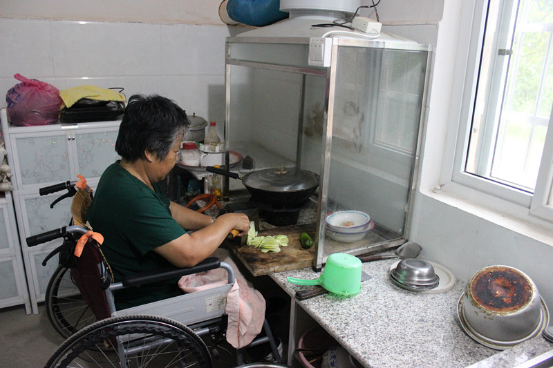 Ruan Guanqing tiene los miembros inferiores paralizados. Ella utiliza superficies de trabajo que estén al nivel de su silla de ruedas. La nueva cocina le permite cocinar sin necesidad de ayuda. Xinyang, provincia de Henan.