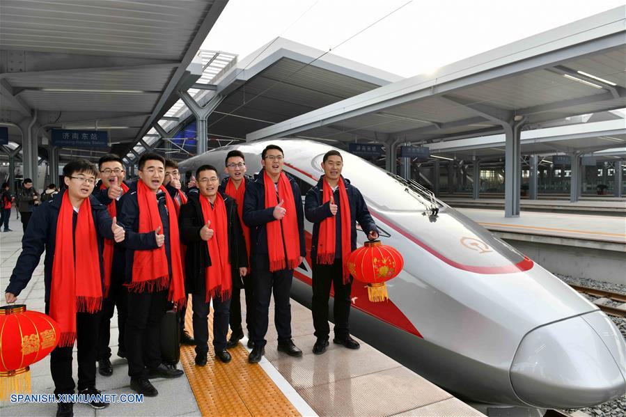 SHANDONG, diciembre 26, 2018 (Xinhua) -- Constructores que participaron en la construcción de la línea del Ferrocarril de alta velocidad Jinan-Qingdao posan para una fotografía grupal frente a un tren en la Estación del Ferrocarril Jinan Este, en la provincia de Shandong, en el este de China, el 26 de diciembre de 2018. El ferrocarril de alta velocidad entre las ciudades chinas Jinan y Qingdao, en servicio desde el miércoles, permite el acceso a redes de comunicaciones 4G y tendrá 5G en el futuro, según fuentes del sector ferroviario de Jinan. (Xinhua/Guo Xulei)