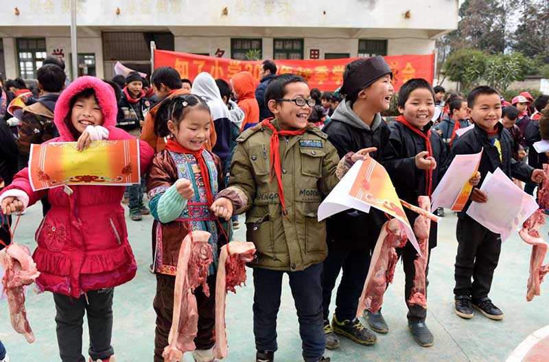 Los estudiantes de Grinning son galardonados con carne de cerdo por su buen desempeño académico en una escuela primaria de Liuzhou, Región Autónoma Guangxi Zhuang. [Foto: Gong Pukang/ Chinadaily.com.cn]