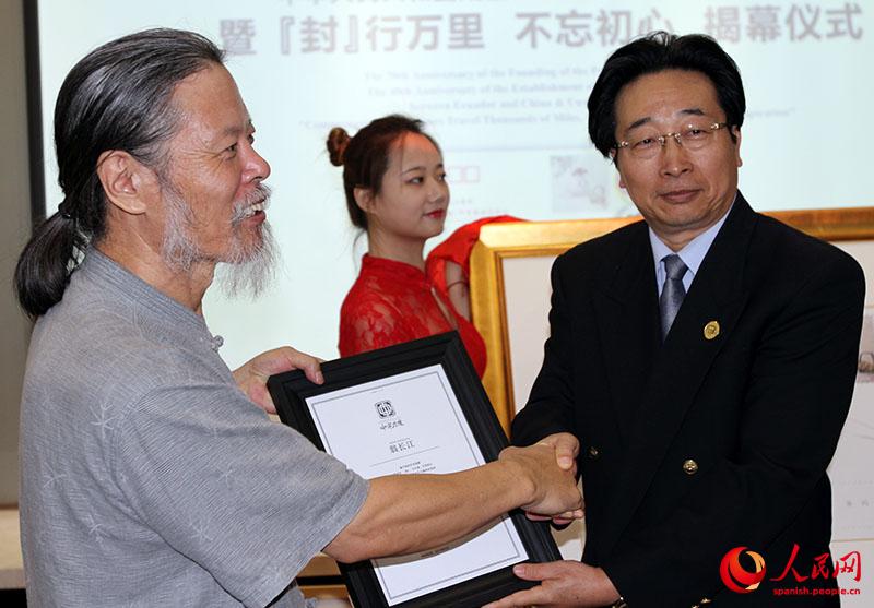 Wang Hua (a la izquierda), subsecretario de la Fundación China para la Paz y el Desarrollo, entregó un reconocimiento al maestro Weng Changjiang durante la presentación del sobre postal artístico China-Ecuador. Beijing, 9 de agosto del 2019. (Foto: YAC)