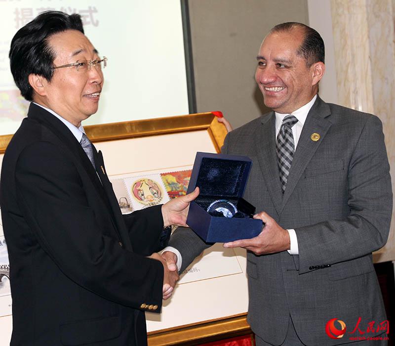 Carlos Larrea (a la derecha), embajador de Ecuador en China recibe un presente de manos de Wang Hua, subsecretario de la Fundación China para la Paz y el Desarrollo, durante la presentación del sobre postal artístico China-Ecuador. Beijing, 9 de agosto del 2019. (Foto: YAC)