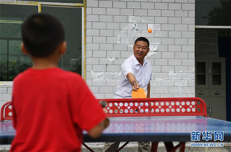 Wu Guoxian juega al tenis de mesa con un estudiante en la Escuela Primaria Gugang, el 27 de agosto de 2019. [Foto / Xinhua]