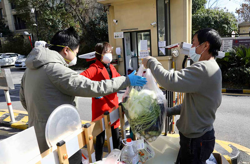 Los residentes buscan las verduras que compraron en la puerta de una comunidad residencial en Wuhan, provincia de Hubei, 18 de febrero del 2020. [Foto: Zhu Xingxin / China Daily]