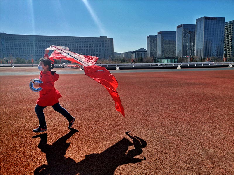 Una chica vuela una cometa en la pista de atletismo del Centro Olímpico de Deportes de Jinan, 22 de febrero del 2020. [Foto: Qian Han/ China Daily] 