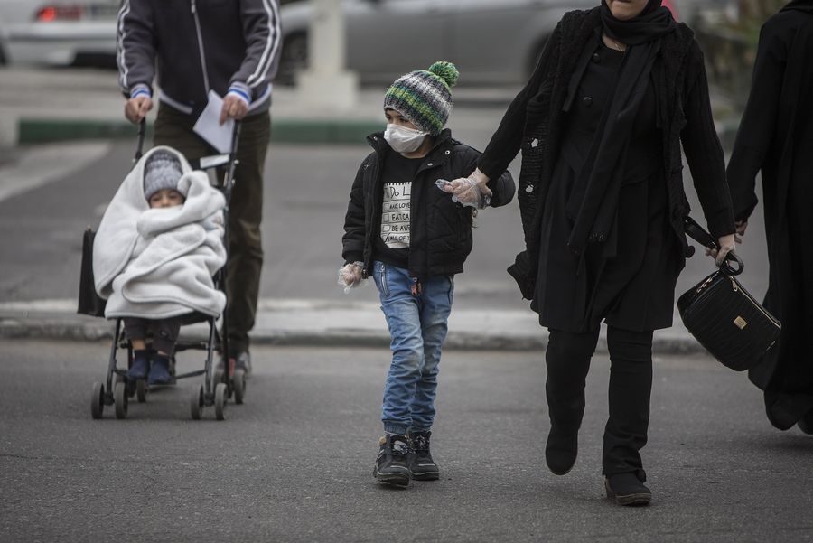 Imagen del 7 de marzo de 2020 de un niño usando una mascarilla cruzando una calle, en Teherán, Irán. (Xinhua/Ahmad Halabisaz)
