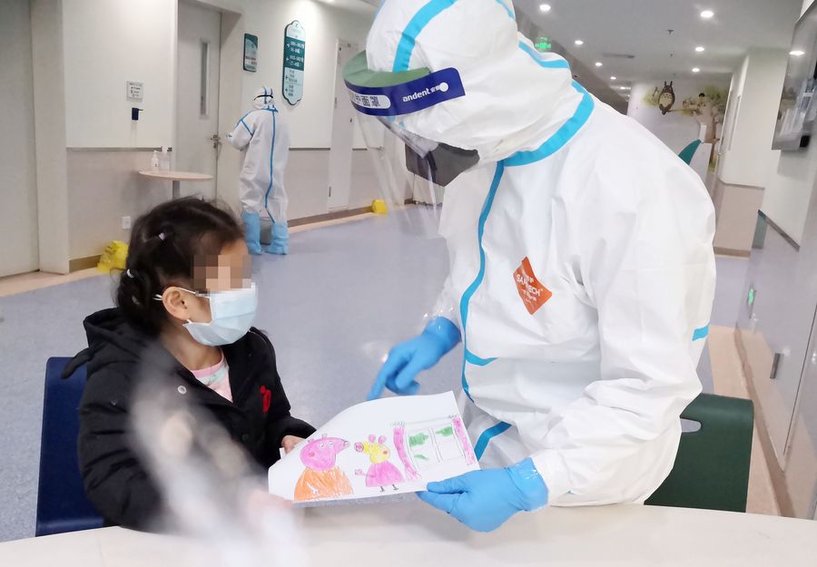 Imagen tomada con un dispositivo móvil del 28 de febrero de 2020 de la enfermera Yang Liu recibiendo un dibujo como un regalo de una niña infectada con neumonia del nuevo coronavirus en una sala en el Hospital Infantil de Wuhan, en Wuhan, provincia de Hubei, en el centro de China. (Xinhua)