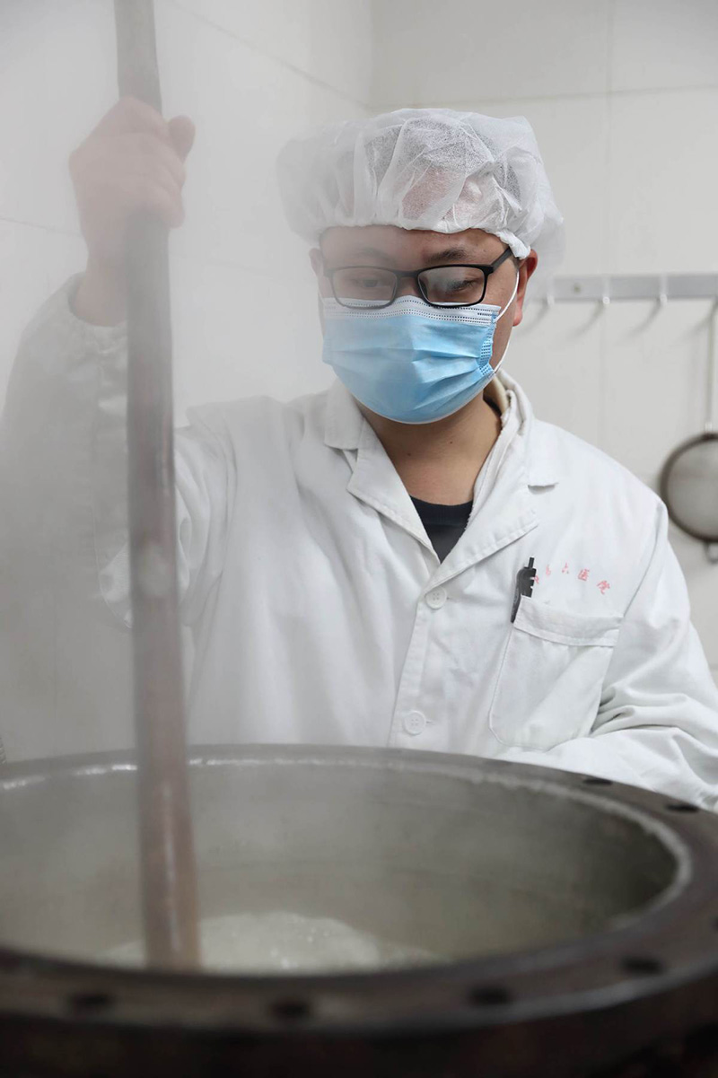 Cai Zehao, farmacéutico del hospital, prepara un remedio de medicina tradicional china. [Foto por Wang Jing / China Daily]