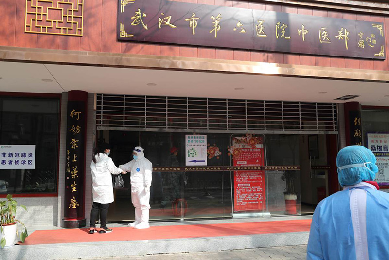 Un trabajador verifica la temperatura de un visitante en la entrada del departamento de medicina tradicional china del hospital. [Foto por Wang Jing / China Daily]