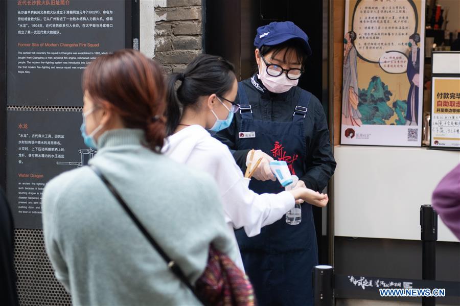 Un miembro del personal comprueba la temperatura corporal de un cliente en un restaurante de Changsha, provincia de Hunan.
