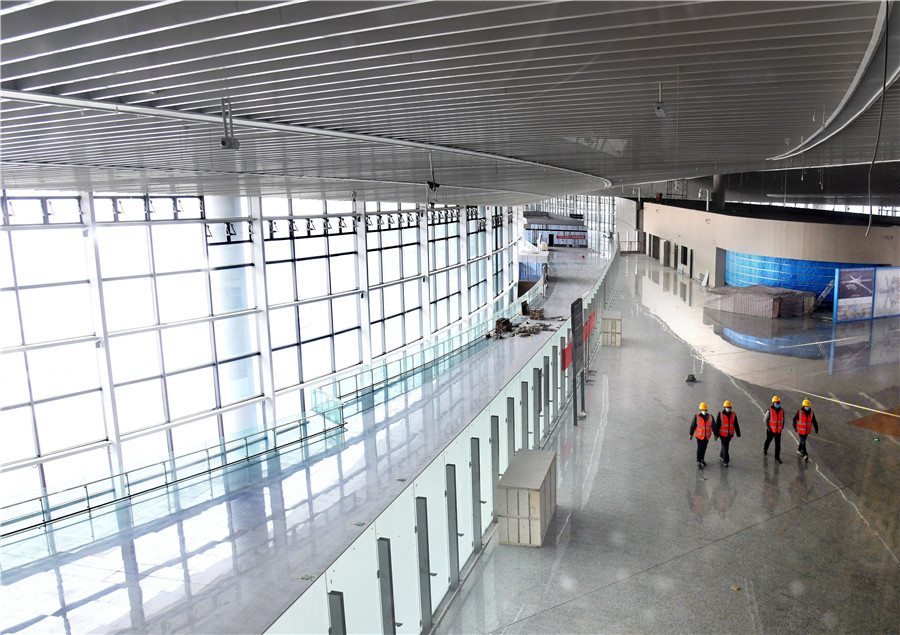 El personal de construcción pasa frente a una sala terminal del Aeropuerto Internacional Jiaodong de Qingdao, provincia de Shandong, este de China, el 25 de marzo de 2020. [Foto / Xinhua]
