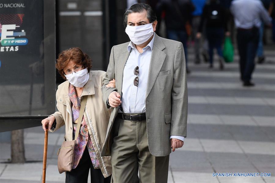 Personas portan mascarillas mientras caminan en una calle en Santiago, capital de Chile, el 21 de abril de 2020. Chile aumentó a 10.832 el número de casos de la enfermedad causada por el nuevo coronavirus (COVID-19), de los cuales 147 han muerto, informó el martes el Ministerio de Salud del país. (Xinhua/Jorge Villegas)