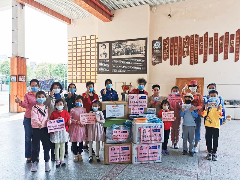 Alumnos de la Escuela Primaria Datong y familiares posan para una foto mientras empacan las máscaras que donaron a la Escuela Lincoln Minster de Reino Unido. [Foto: proporcionada a China Daily] 