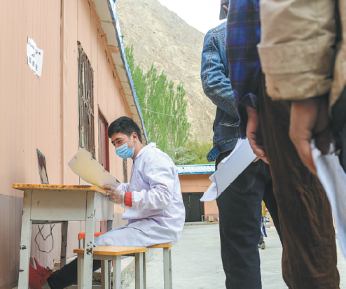 Eziz Hudaberdi verifica la información de salud de un aldeano en la clínica del pueblo de Yaragiz. [Foto / Xinhua]