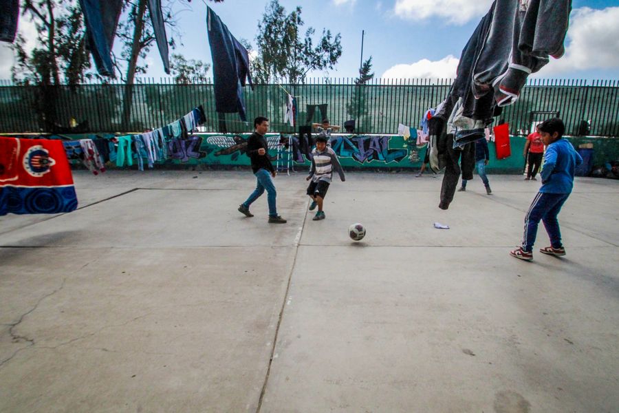 Migrantes juegan al fútbol en el Albergue Nueva Misión Agape, en Tijuana, México, el 4 de abril de 2020. El coronavirus aplazó el proceso de asilo en Estados Unidos de migrantes centroamericanos, sudamericanos y caribeños que aguardaban en el norte de México, lo que complicó su precaria economía. (Xinhua/Joebeth Terriquez)