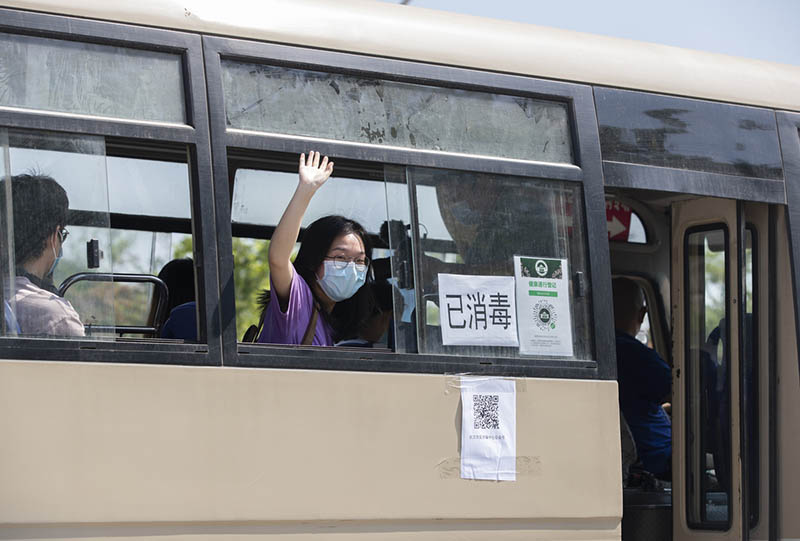 Una estudiante saluda mientras espera para regresar a su dormitorio en un autobús escolar en la Universidad de Wuhan, provincia de Hubei, 8 de junio del 2020. [Foto: Ke Hao/ China Daily]