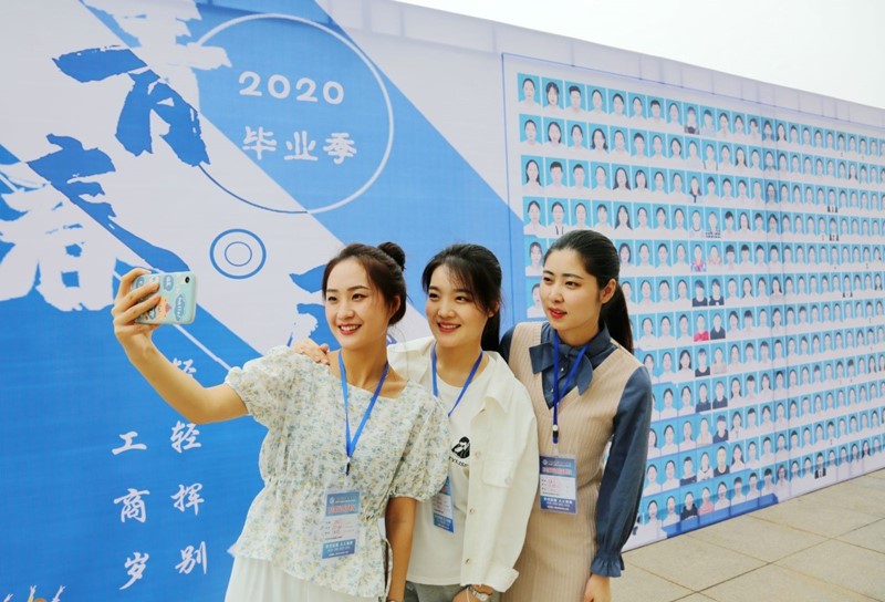 Graduados del Colegio Vocacional Nantong de Ciencia y Tecnología, en la provincia de Jiangsu, posan para una foto frente a una placa, 16 de mayo del 2020. (Foto: Feng Kaimin/ Pueblo en Línea)