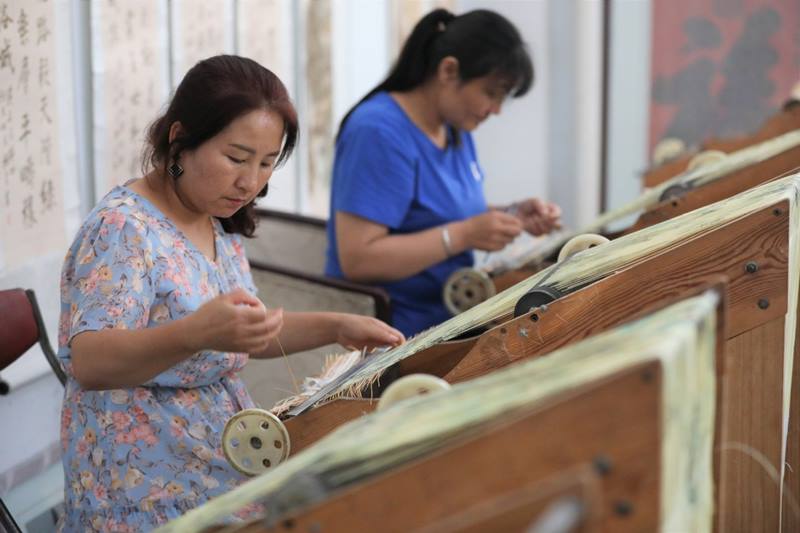 Los estudiantes de Wei trabajan en pinturas de tejido en papel en el condado de Zhuanglang, en la ciudad de Pingliang, en la provincia de Gansu, en el noroeste de China, el 8 de julio. [Foto: Xinhua]