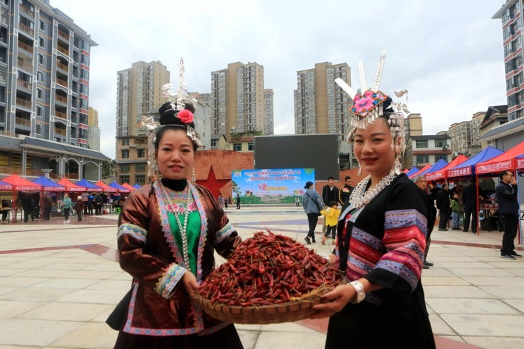 Dos vendedoras muestran pimientos secos en un evento de promoción de productos agrícolas, productos locales característicos y artesanías tradicionales en el Día Nacional de Alivio de la Pobreza de 2020 en el condado Rongjiang, provincia de Guizhou, en el suroeste de China, el 17 de octubre. (Foto de Yang Wenshu / Pueblo en Línea)