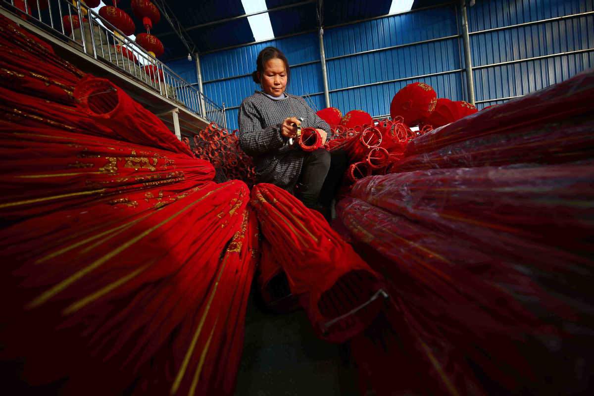 Una empleada inspecciona los faroles chinos en el condado Danzhai, Qiandongnan Miao y prefectura autónoma de Dong, provincia de Guizhou, 20 de diciembre del 2020. [Foto: Huang Xiaohai/ China Daily]