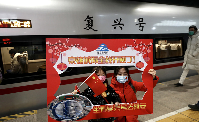 Los pasajeros y los miembros de la tripulación del tren se hacen fotos antes de subir al tren de alta velocidad que une Beijing y la Nueva Área de Xiong´an, en la Estación de Ferrocarriles Oeste de Beijing, el 27 de diciembre de 2020. [Foto de Zou Hong / chinadaily.com.cn]