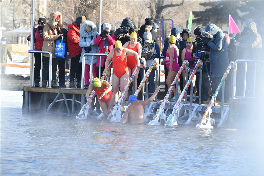 Los entusiastas de la natación de invierno se sumergen en el lago helado de Nanhu para expresar buenos deseos para el nuevo año en Changchun, provincia de Jilin, el viernes. [Foto proporcionada a chinadaily.com.cn]