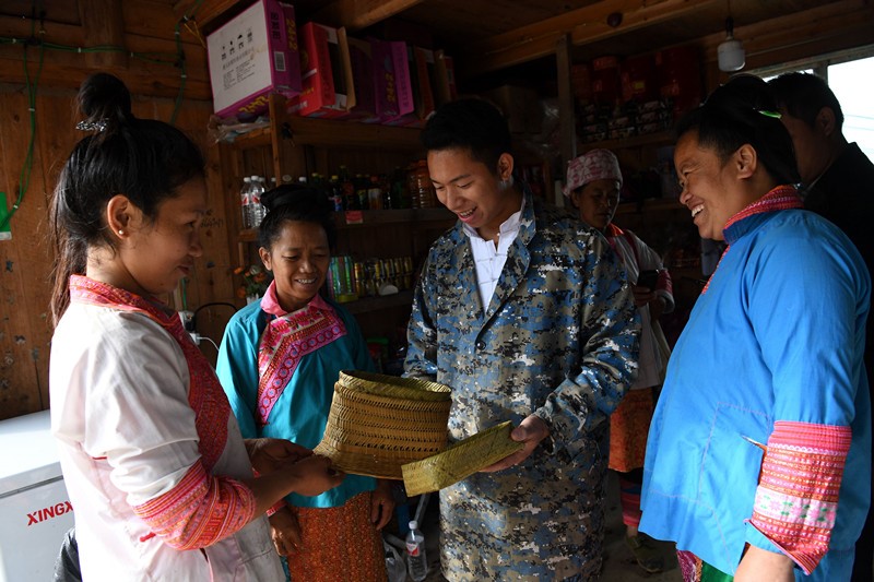 Pan Fangjian (tercero por la izquierda) dirige una empresa de tecnología de redes en el condado de Rongjiang, en la provincia de Guizhou, al suroeste de China. Su compañía también ayuda a otras empresas de logística y de transporte urgente a entregar paquetes desde el condado a las aldeas. En la actualidad, su empresa dirige más de 120 sitios de recogida de paquetes en 100 aldeas de los condados de Rongjiang y Congjiang. La foto muestra a Pan hablando con los aldeanos en un sitio de recogida de paquetes, el 18 de noviembre de 2020. (Pueblo en línea/Wang Bingzhen)