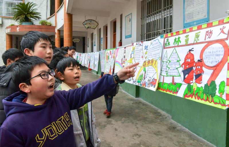 El 29 de diciembre de 2020, los estudiantes de la escuela primaria Xiaohe en la ciudad de Guang'an, provincia de Sichuan, observaban un poster escrito a mano sobre la prevención de incendios forestales creado por estudiantes de varias clases. Zhang Guosheng / Pueblo en Línea