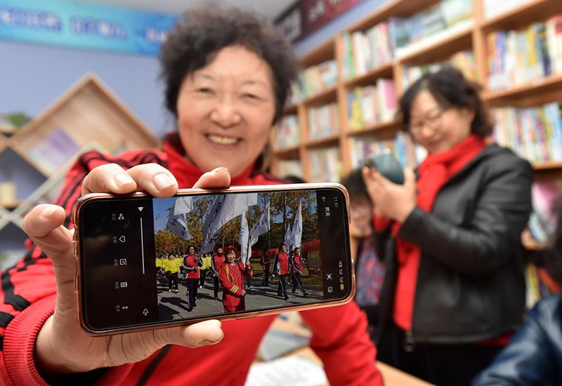 El 12 de noviembre de 2020, en la biblioteca comunitaria de Xinsheng, en el distrito Hanjiang de Yangzhou, provincia de Jiangsu, una mujer mayor de la comunidad, que domina "nuevas habilidades" como la grabación de videos con su teléfono inteligente, mostró sus obras de videos sobre su vida como jubilada. Imagen de Zhuang Wenbin / Pueblo en Línea