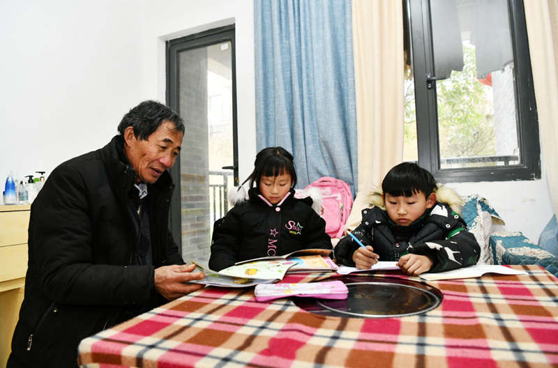 Li Changde y sus nietos disfrutan de su nueva reubicación en una comunidad construida para el alivio de la pobreza, antigua ciudad de Shexiang, Dafang, 23 de diciembre del 2020.