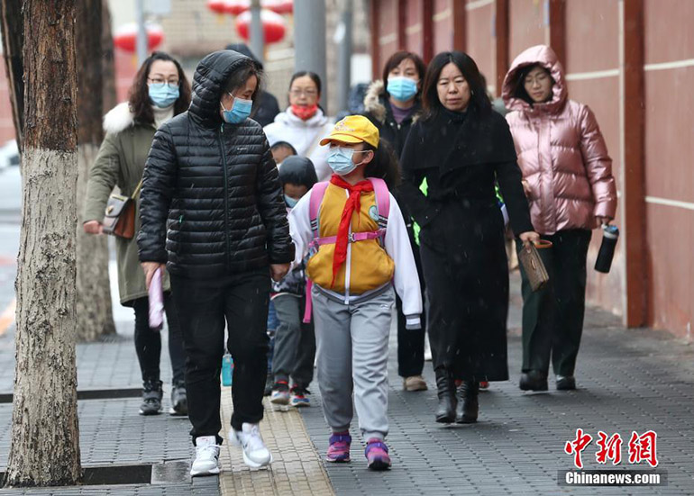 Los estudiantes y sus padres caminan hacia una escuela en el distrito Fengtai de Beijing el 1 de marzo de 2021. La gente llevaba ropa gruesa debido al clima frío, la lluvia y la nieve. Todos los estudiantes de guarderías, además de escuelas primarias y secundarias en Beijing comenzaron las clases presenciales del semestre de primavera el 1 de marzo, la fecha de inicio habitual. [Foto / Chinanews.com]
