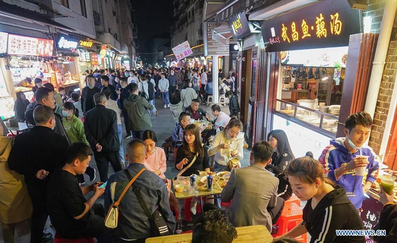 La gente come aperitivos en un callejón en Wuhan, provincia de Hubei, en el centro de China, el 28 de marzo de 2021.