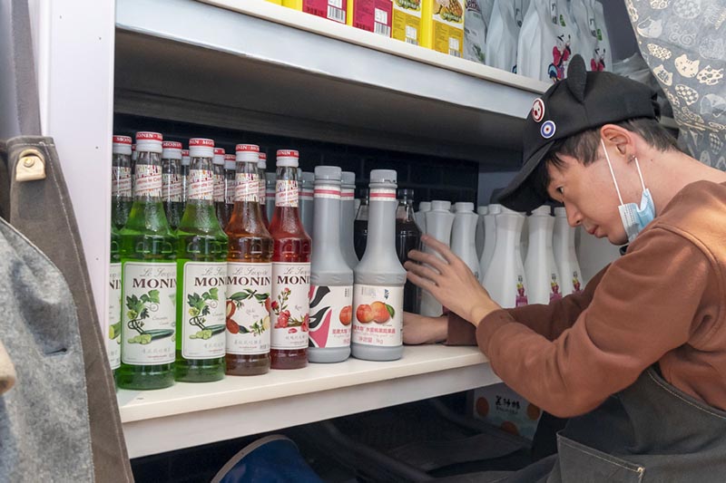A Ken organiza productos en la estantería Café Hinichijou de Shanghai. [Foto: Xinhua]