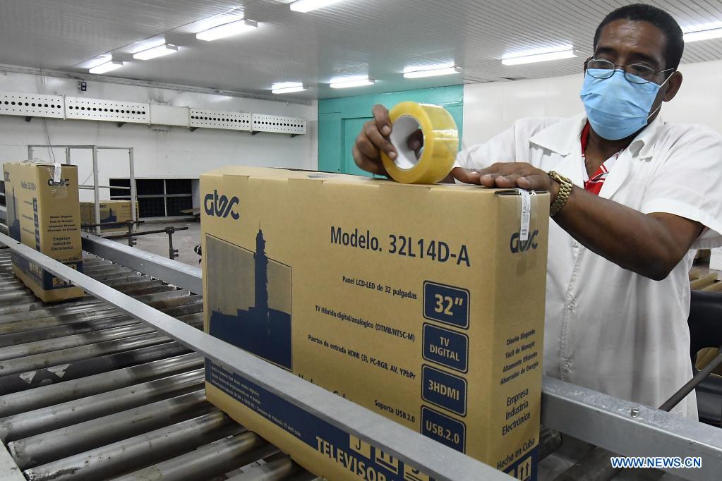 Imagen del 21 de mayo de 2021 de un trabajador empacando un televisor en los talleres de la Empresa Industria Electrónica "Comandante Camilo Cienfuegos", en La Habana, capital de Cuba. Cuba espera dar un impulso a la expansión de la televisión digital con norma china mediante la producción este año de 318.000 cajas decodificadoras, en el contexto de la pandemia de la enfermedad del nuevo coronavirus (COVID-19) y los efectos de las sanciones económicas del bloqueo de Estados Unidos contra el país. (Xinhua/Joaquín Hernández)