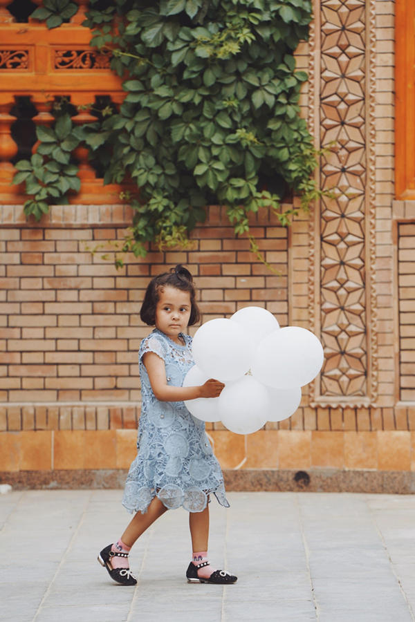 Una niña Uygur juega con globos a lo largo de una calle en el casco antiguo de Tuancheng, la ruta peatonal más famosa de la ciudad de Hotan, en la región autónoma Uygur de Xinjiang, noroeste de China, el 22 de mayo de 2021 (Pueblo en Línea / Yuan Meng).