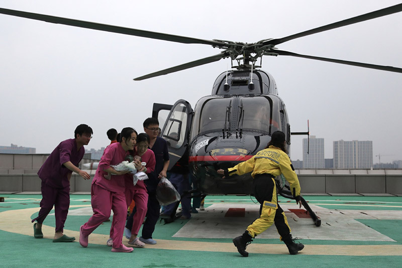 El personal médico y los rescatistas trasladan a un bebé en un helicóptero desde el inundado Hospital Cardiovascular Central de China de Fuwai en Zhengzhou, capital de la provincia central china de Henan, el 22 de julio de 2021. [Foto de Wang Jing / chinadaily.com.cn]