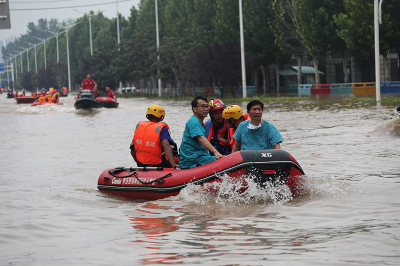 Los rescatistas ayudan a trasladar al personal médico varado con un bote inflable en el Hospital Cardiovascular Central de China de Fuwai en Zhengzhou, capital de la provincia central china de Henan, el 22 de julio de 2021. [Foto de Wang Jing / chinadaily.com.cn]