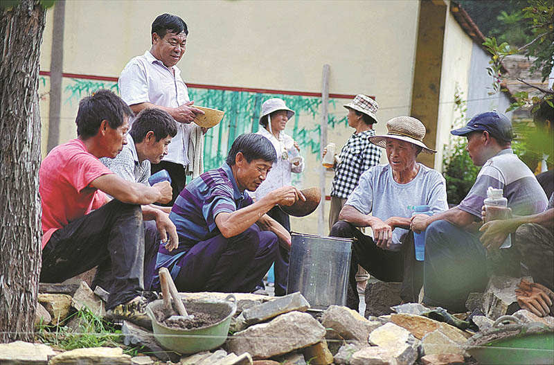Feng y otros voluntarios descansan en el sitio de construcción. [Foto de Zhao Dongshan y Fu Youmin / para China Daily]
