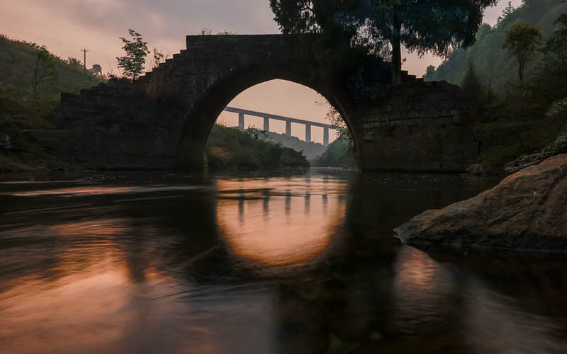 El antiguo puente de Mengjia, construido en 1882, aparece en esta imagen junto al gran puente del río Yinpo del ferrocarril de alta velocidad Guiyang-Nanning (en la distancia) en el condado Dushan, provincia de Guizhou, en el suroeste de China, el 1 de abril de 2021. (Xinhua / Liu Xu)