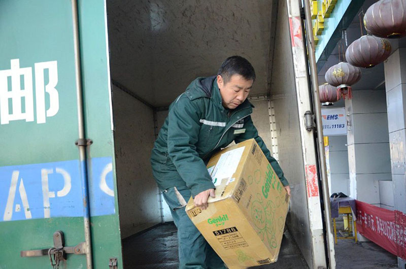 Wang Shouqiu baja un paquete del camión. [Foto proporcionada a chinadaily.com.cn]