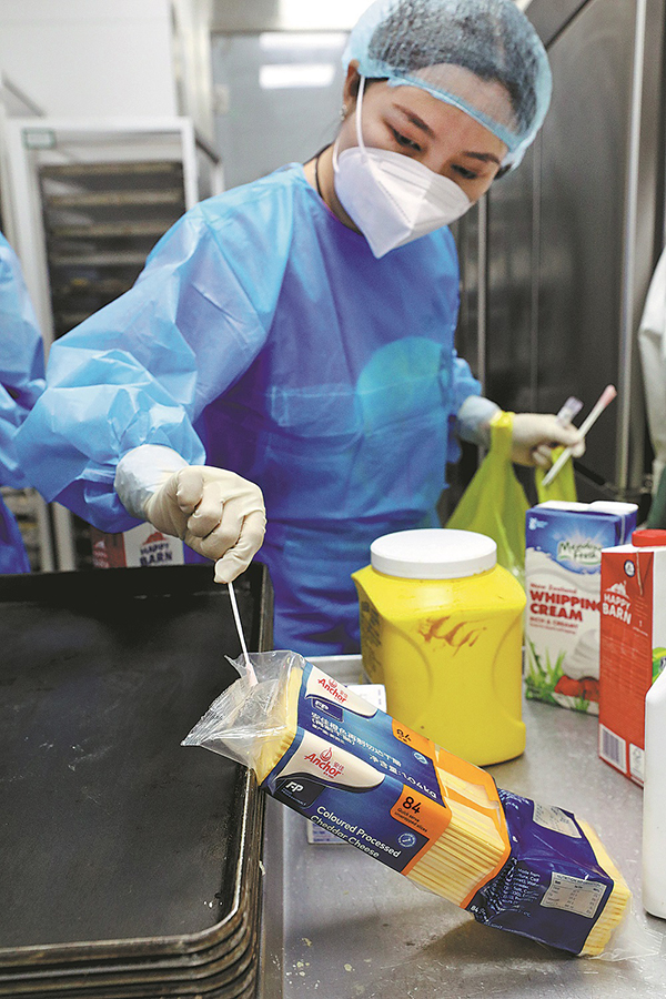 Un miembro del equipo de prueba recolecta muestras de ácido nucleico en una panadería, 13 de septiembre. (Foto: Zhu Xingxin/ China Daily)