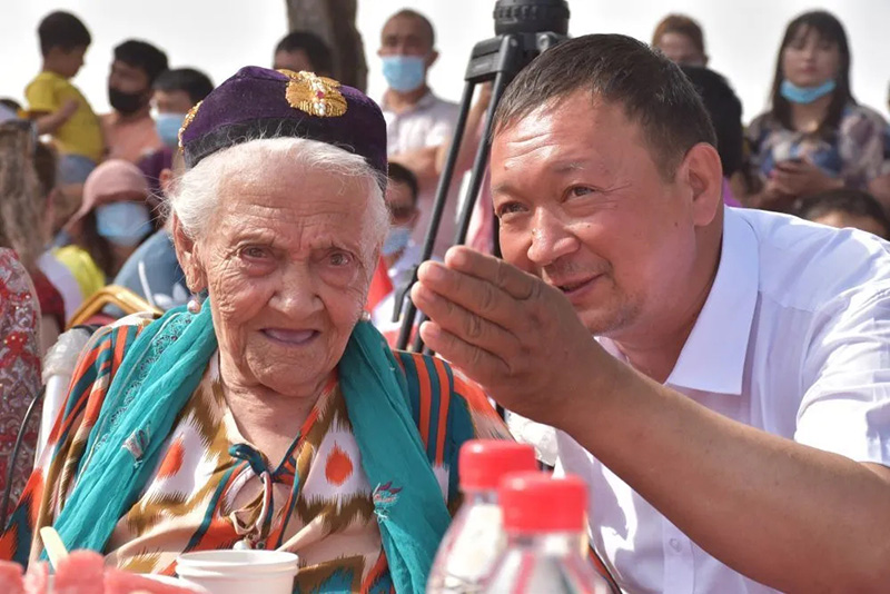 El 25 de junio de 2020, Alimihan Seyiti (izquierda) habló con su nieto en el lugar donde celebraba su 134 cumpleaños en el condado Shule, Xinjiang.  (Foto: cuenta oficial del Diario del Pueblo en Wechat)